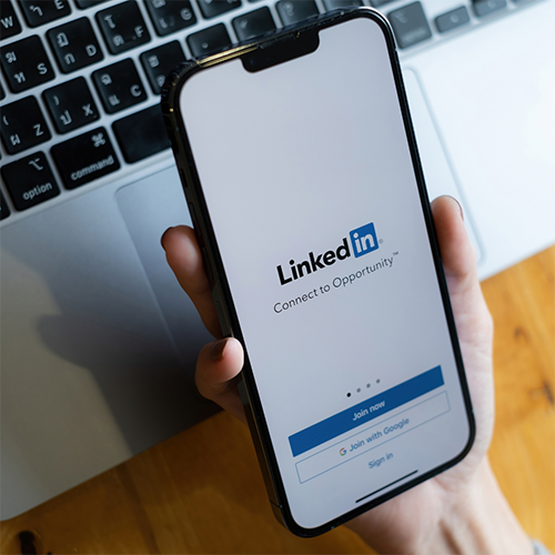 Hand holding phone displaying LinkedIn login screen